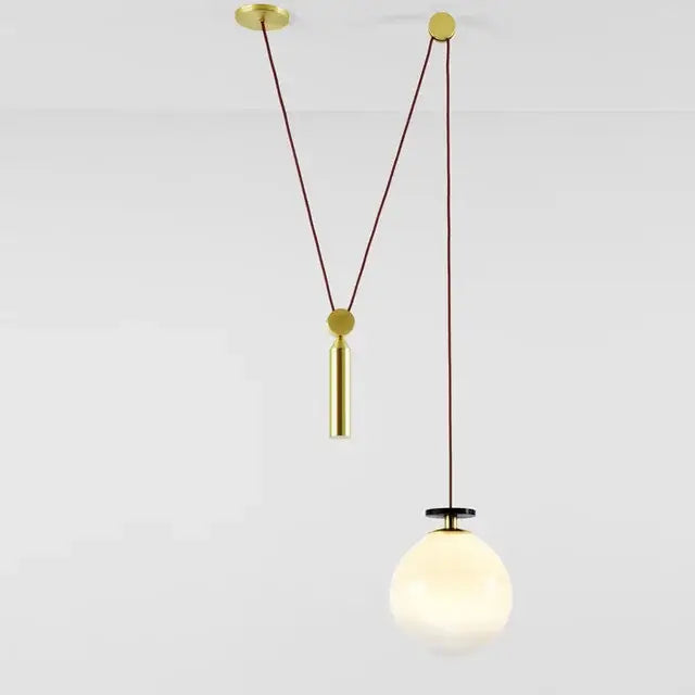 Gold-toned pendant light with spherical frosted glass shade and brass hardware for modern dining rooms chandelier