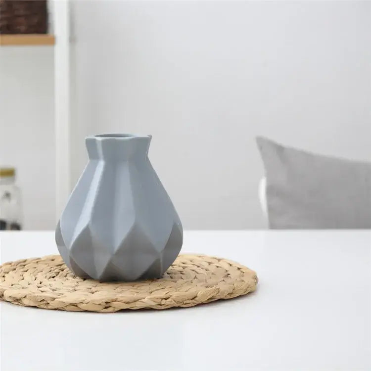 A sleek matte gray decorbites ceramic diamond vase with geometric faceted design on woven placemat for living room decor