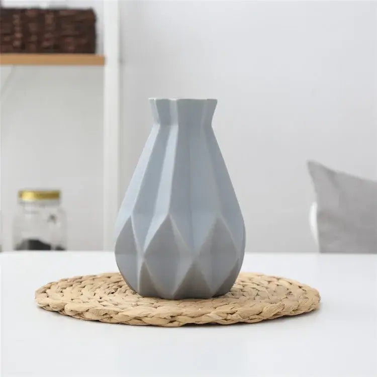 A sleek matte gray decorbites ceramic diamond vase with a geometric faceted design on a woven placemat