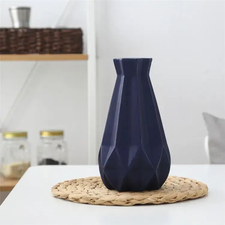 A sleek navy blue decorbites ceramic diamond vase with a geometric faceted design on a woven placemat
