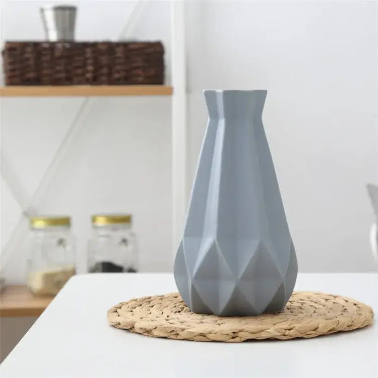A sleek matte gray decorbites ceramic diamond vase with geometric faceted design on woven placemat for modern decor