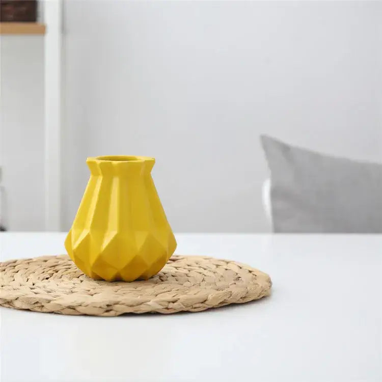 A vibrant yellow decorbites ceramic diamond vase with faceted geometric design on woven placemat for living room decor