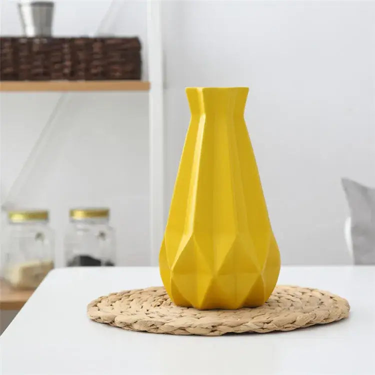 A vibrant yellow decorbites ceramic diamond vase with faceted modern design on woven placemat for living room decor