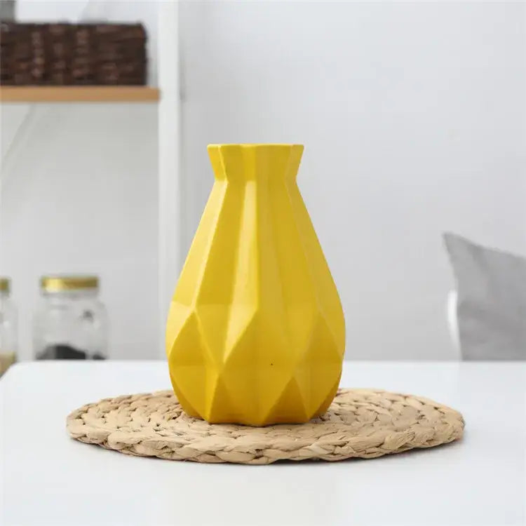 A vibrant yellow decorbites ceramic diamond vase with geometric faceted design on woven placemat for living room decor