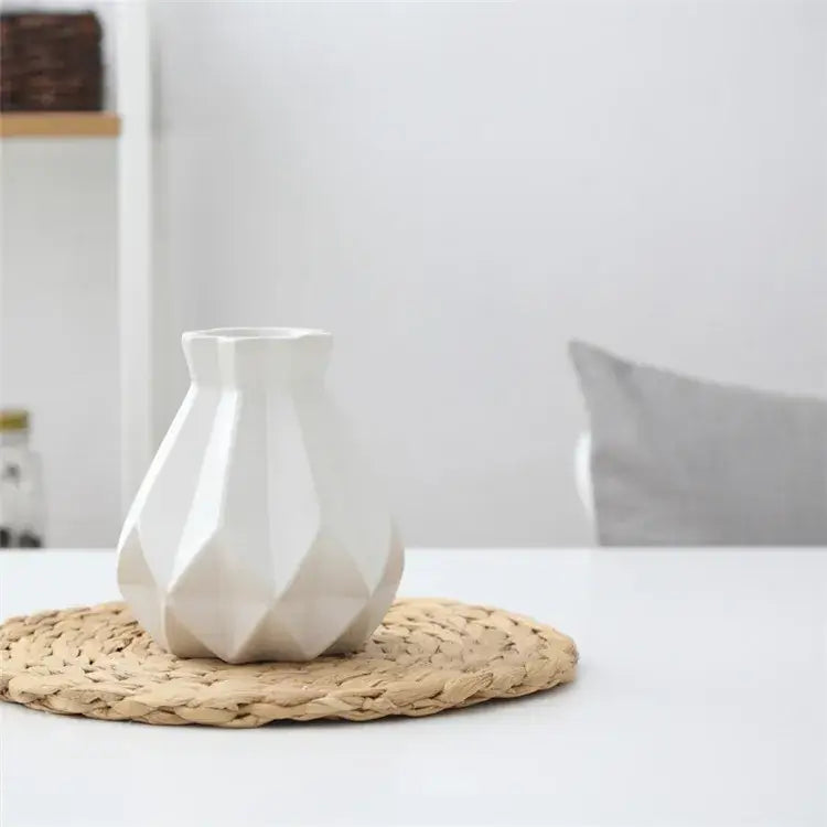 A white decorbites ceramic diamond vase with geometric faceted design on a woven placemat for living room decor