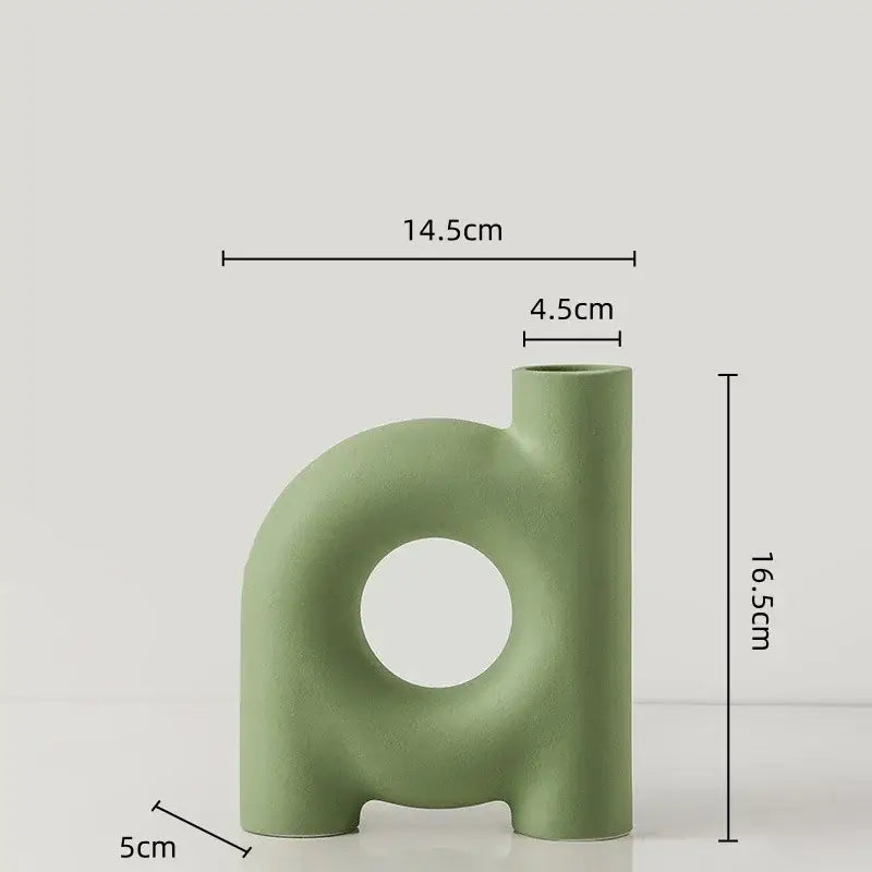 A sleek matte sage green decorbites geometric ceramic vase with a central circular cutout and two short legs for decor