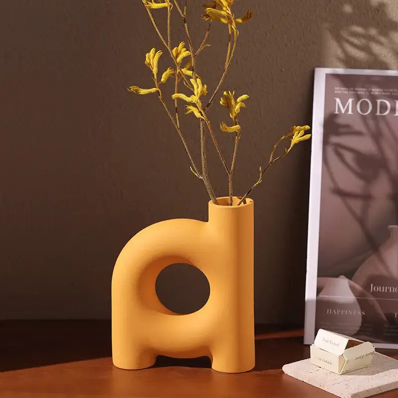 Modern geometric ceramic vase in matte yellow with a d shape and circular cutout from decorbites geometric ceramic collection