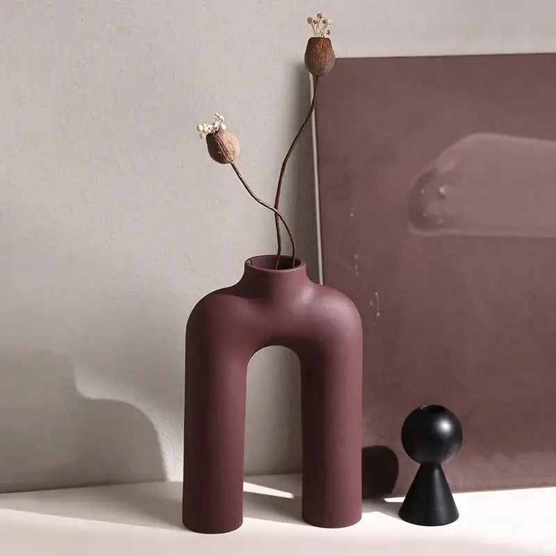 A sleek matte burgundy decorbites geometric ceramic vase with u-shaped design and curved legs for modern living room decor