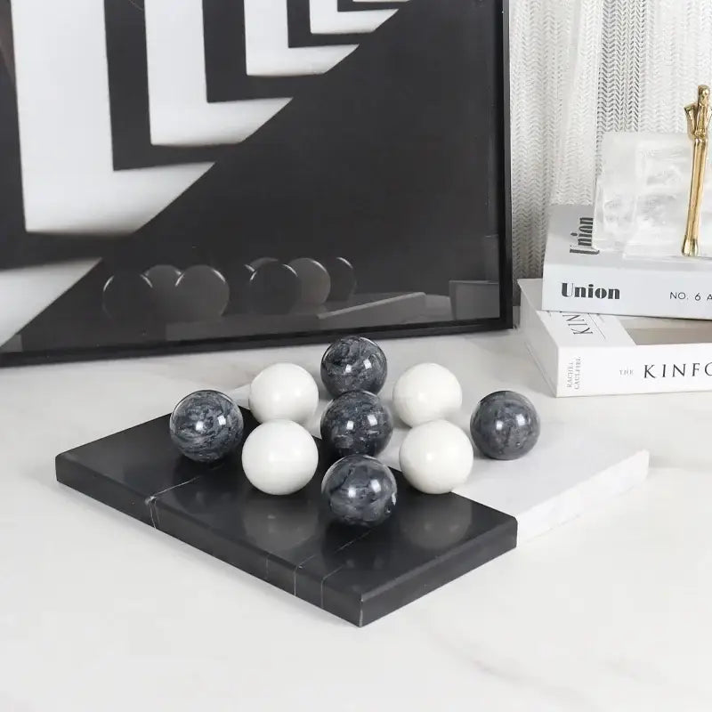 A modern geometric chess ornament set with polished black and white marble spheres on a sleek black marble tray for home decor