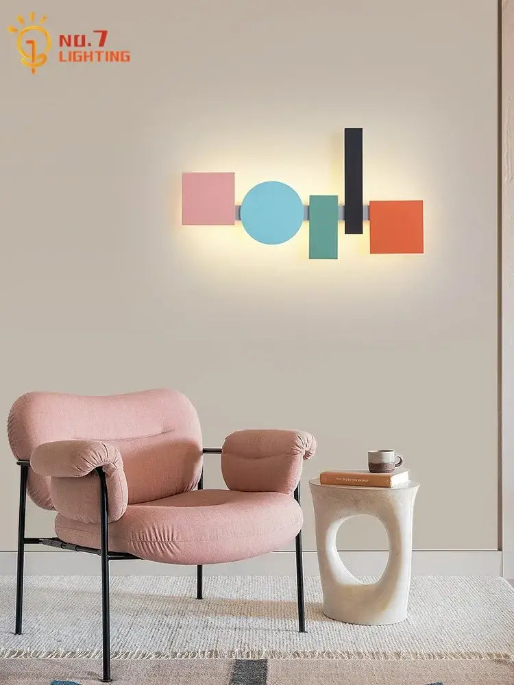 Pastel pink velvet armchair with black metal frame complementing modern geometric colorful led acrylic iron wall lamp decorbites