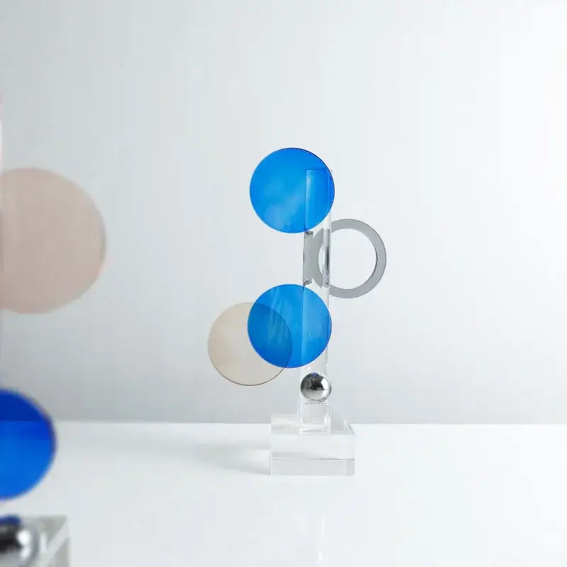A modern geometric crystal circle sculpture with translucent blue and beige discs and metallic silver accents for home decor
