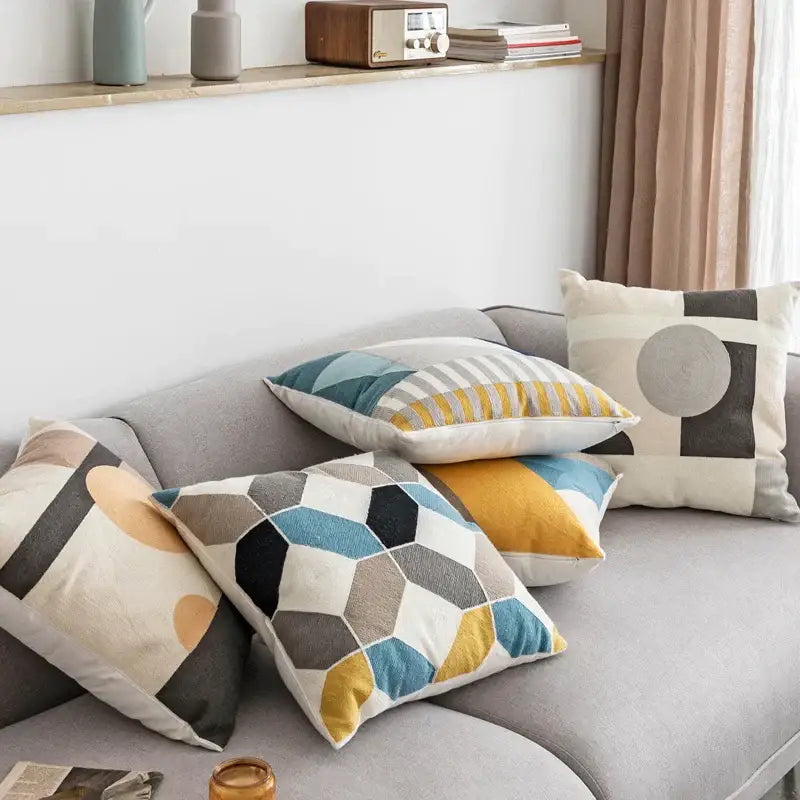 A cozy gray sofa with colorful decorbites geometric embroidery cushion covers in blue yellow black and beige tones