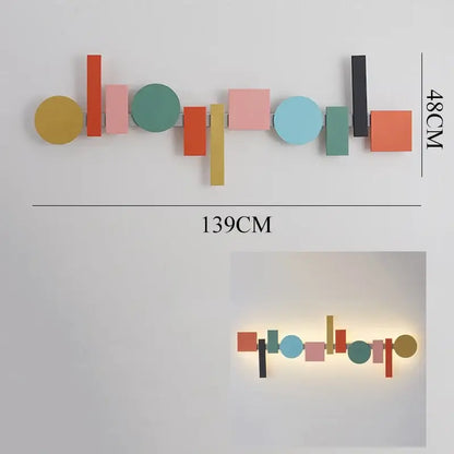 A modern geometric flush mount wall sconce with colorful flat-cut shapes on a sleek metal frame for bedroom decor