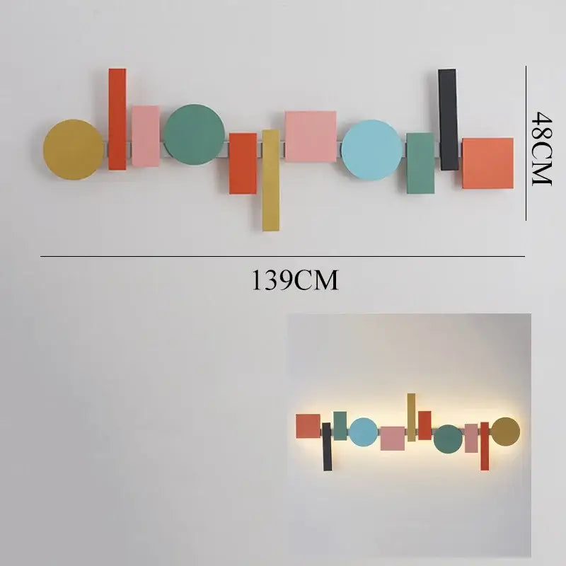 A modern geometric flush mount wall sconce with colorful flat-cut shapes on a sleek metal frame for bedroom decor