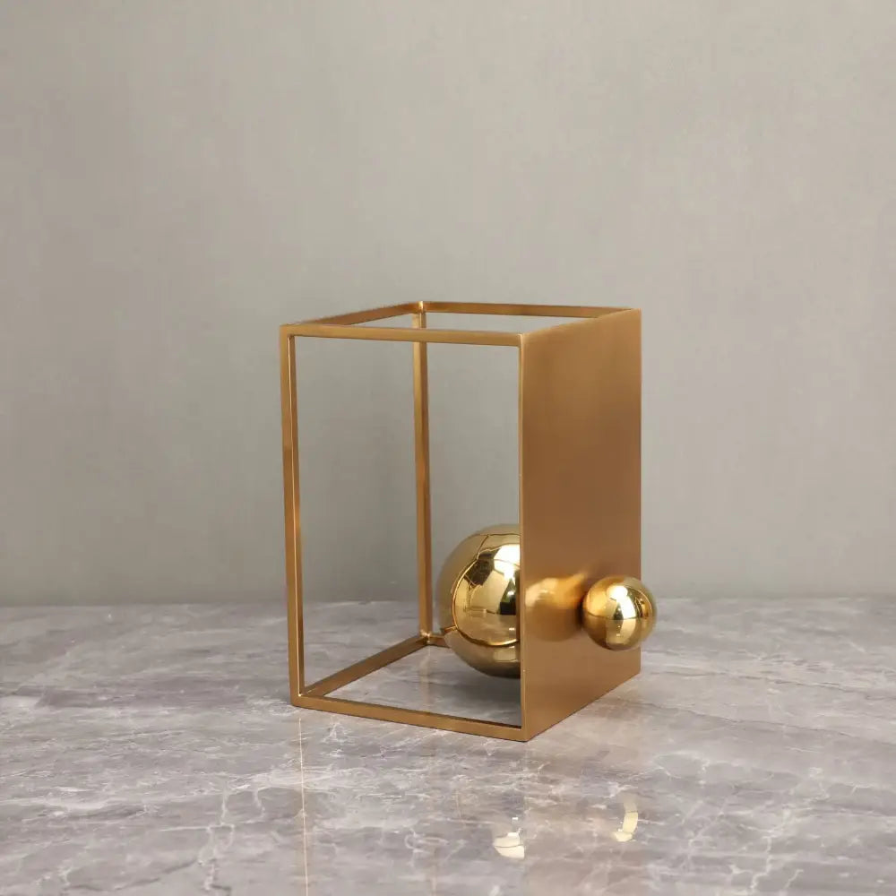Modern geometric gold decorative figurines featuring a minimalist gold-toned cube frame with polished spheres