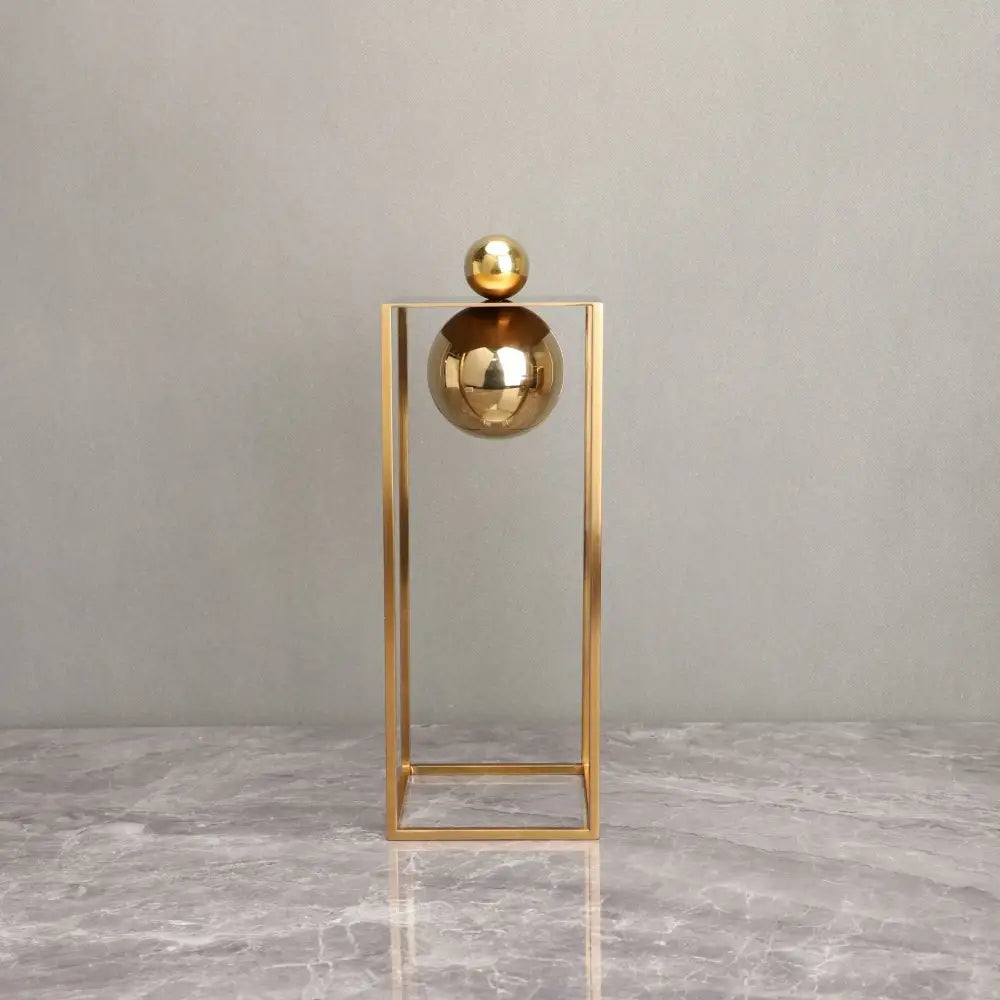 Modern geometric gold frame decorative figurines with gold metallic spheres balanced in a minimalist geometric gold frame sculpture