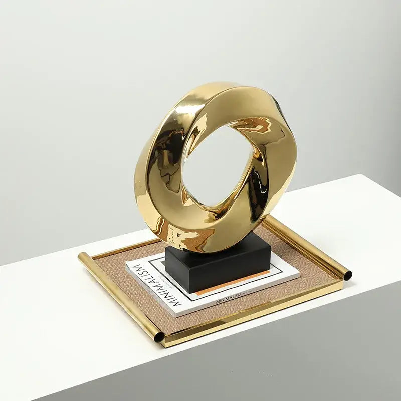 Modern geometric gold hollowed home decor sculpture with smooth reflective surface and intertwined loop design by decorbites