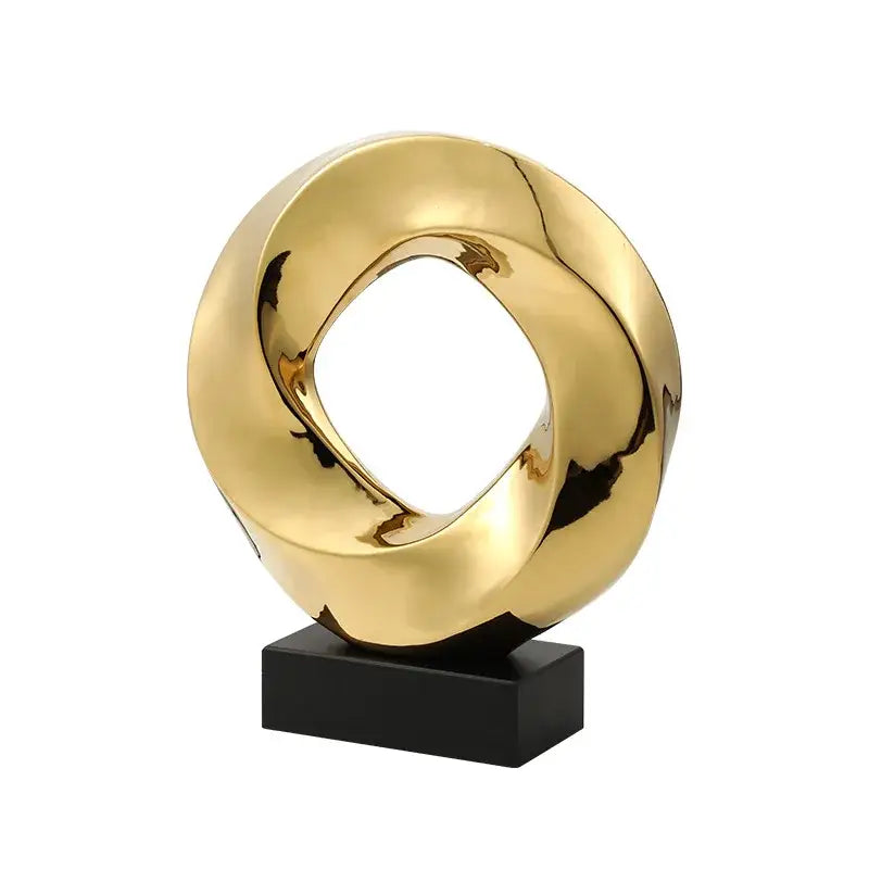 Golden glossy geometric gold hollowed abstract sculpture with twisted ring design on black base for home decor