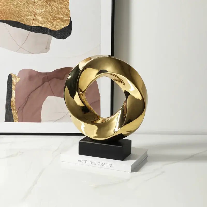 Shiny gold abstract geometric gold hollowed sculpture with intertwined loops on black base for home decor