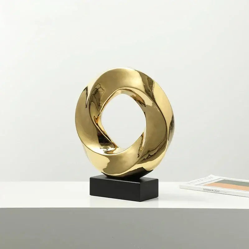 Shiny gold abstract geometric gold hollowed sculpture with intertwined loops on black base for home decor