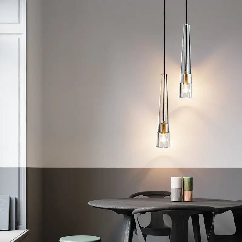 Two modern pendant lights with chrome bodies and gold accents hang above a dark wooden table decorbites crystal led