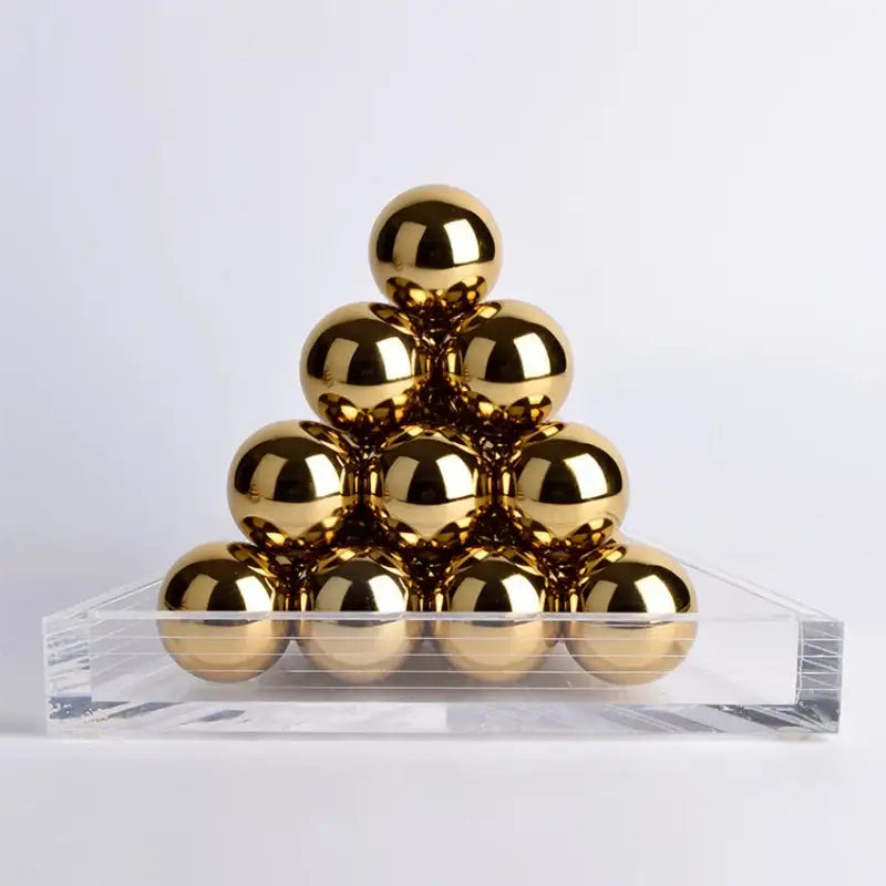 Polished gold metallic spheres in a geometric gold tower set on a clear acrylic base for decorbites geometric gold trays