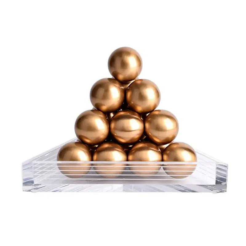 Stack of polished gold-colored metallic spheres arranged in a geometric gold tower on a clear acrylic base decorbites geometric gold