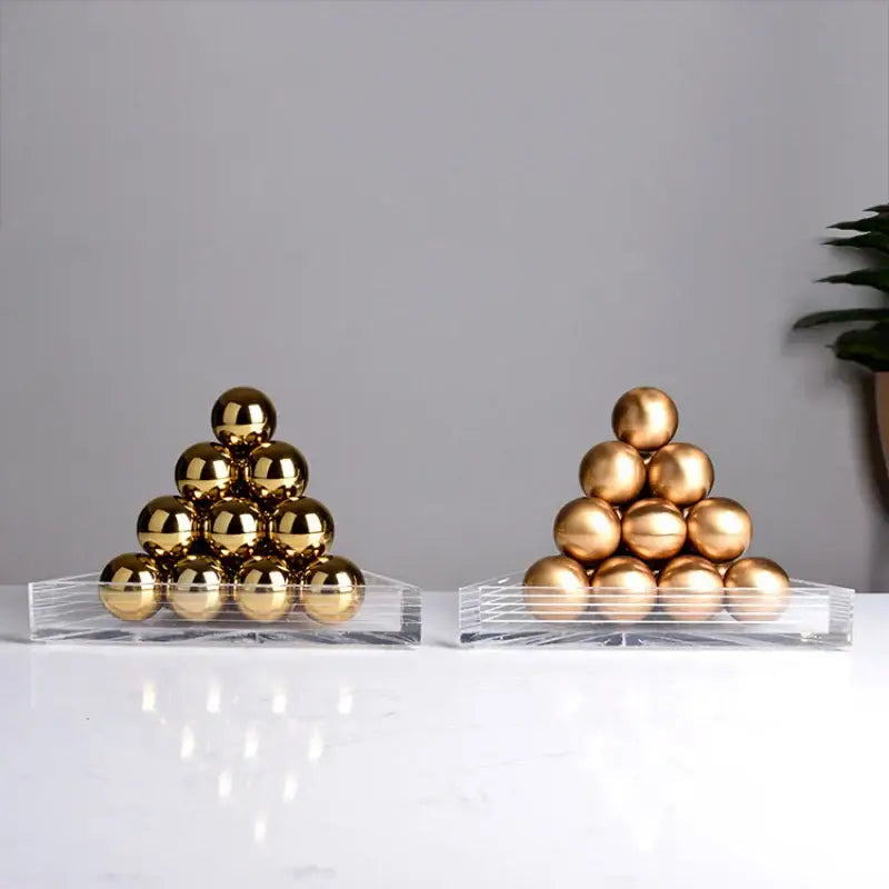 Two pyramid stacks of polished gold metallic spheres on clear acrylic bases in a decorbites geometric gold tower set