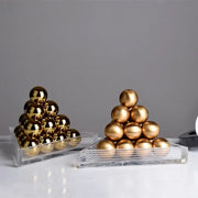 Two stacks of polished gold metallic spheres in clear acrylic trays forming a decorbites geometric gold tower set