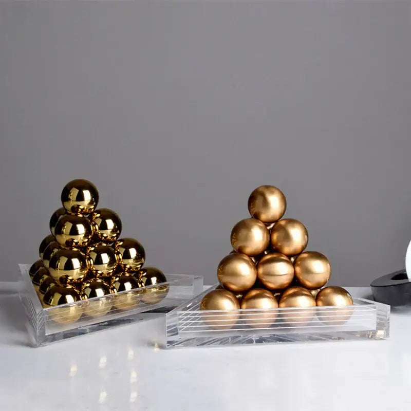 Two stacks of polished gold metallic spheres in clear acrylic trays forming a decorbites geometric gold tower set