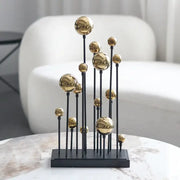 Modern abstract metal sculpture featuring multiple polished geometric golden ball spheres on slender black rods