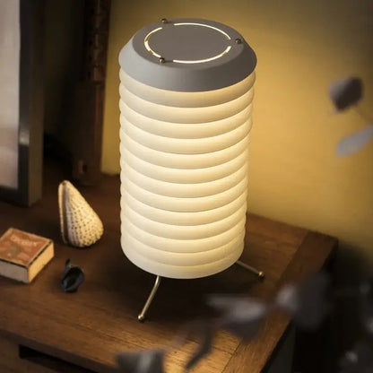 A modern decorbites geometric iron table lamp with a ribbed white body gray top and three slender metal legs for living room decor