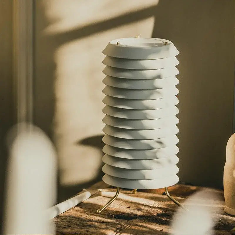 A sleek off-white ceramic iron table lamp with tiered fluted design and gold legs for modern geometric iron decorbites