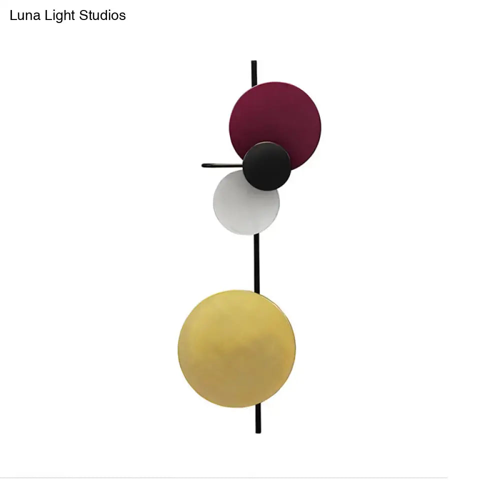 Modern geometric led wall light with stacked burgundy black white and gold discs on black rod in red pink blue tones