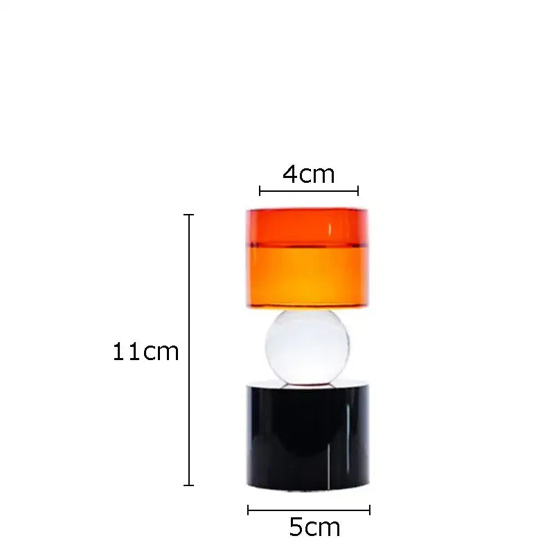 A modern geometric crystal candle holder with translucent orange and clear spheres on a black base for dining room
