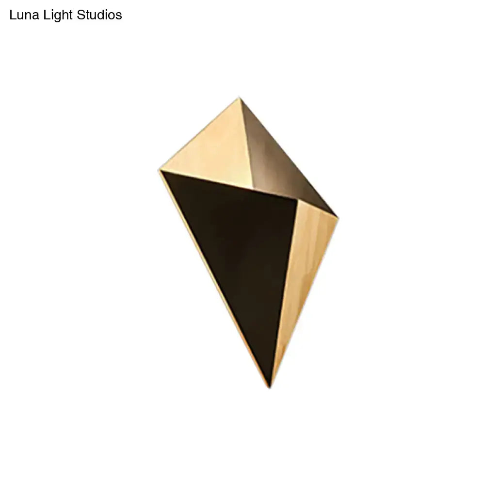 Modern geometric wall sconce made of rubber wood with a two-tone gold and black finish and angular facets for bedroom use
