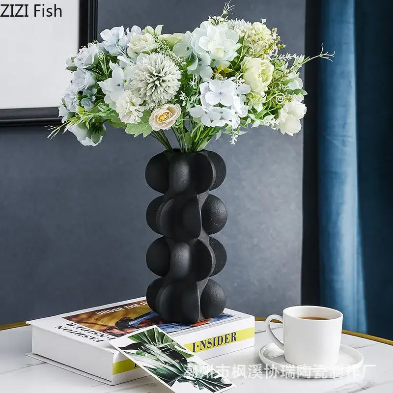 Black ceramic vase with rounded stacked segments holding white and light green flowers for decorbites geometric spiral decor