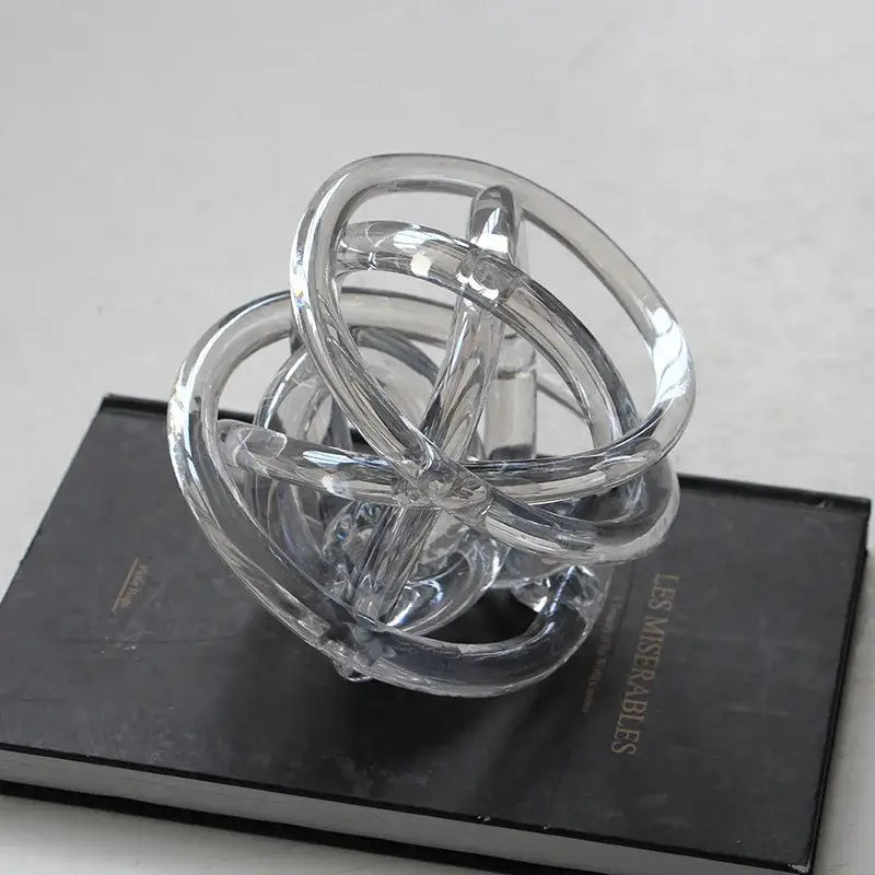 Clear transparent glass coil wound ball sculpture with interlocking rings for modern geometric living room decor
