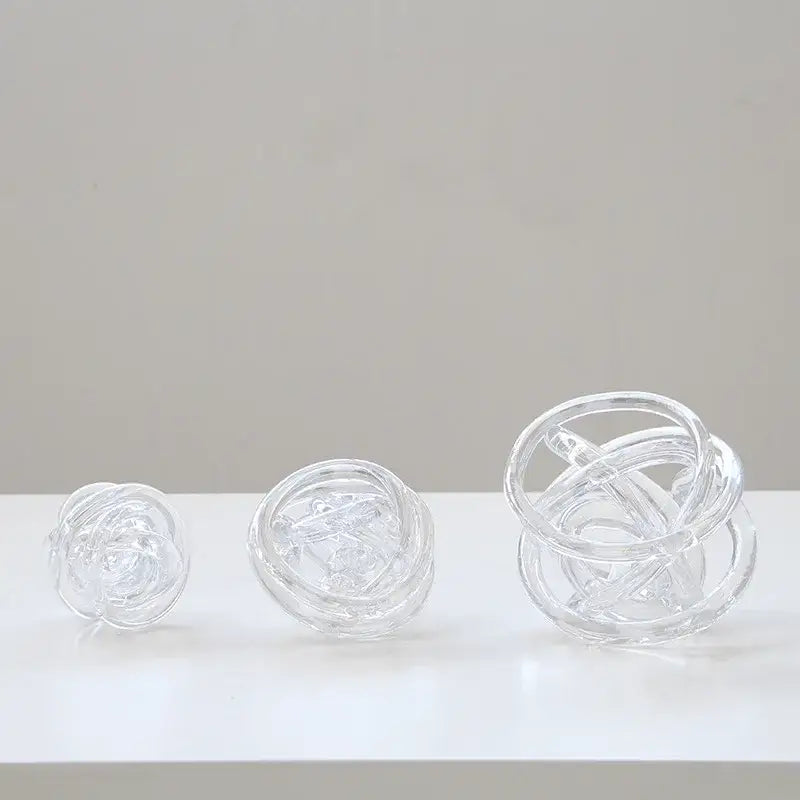 Three transparent glass coil wound balls of varying sizes with intricate interwoven circular designs for living room decor