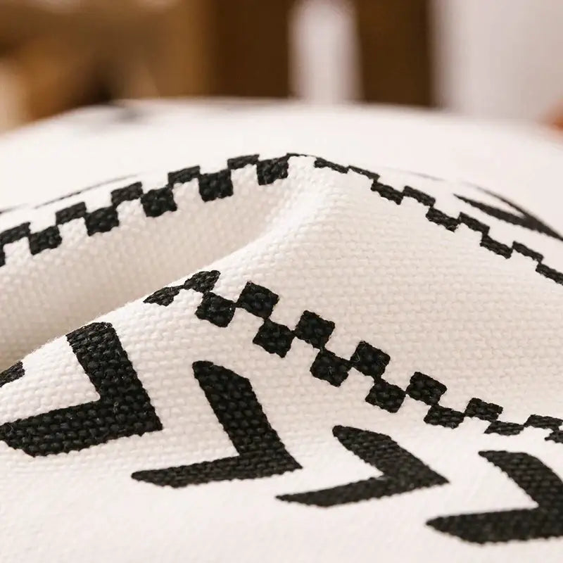 Modern geometric white and black cushion cover with bold patterns and tassels perfect for decorbites brown faux leather decor