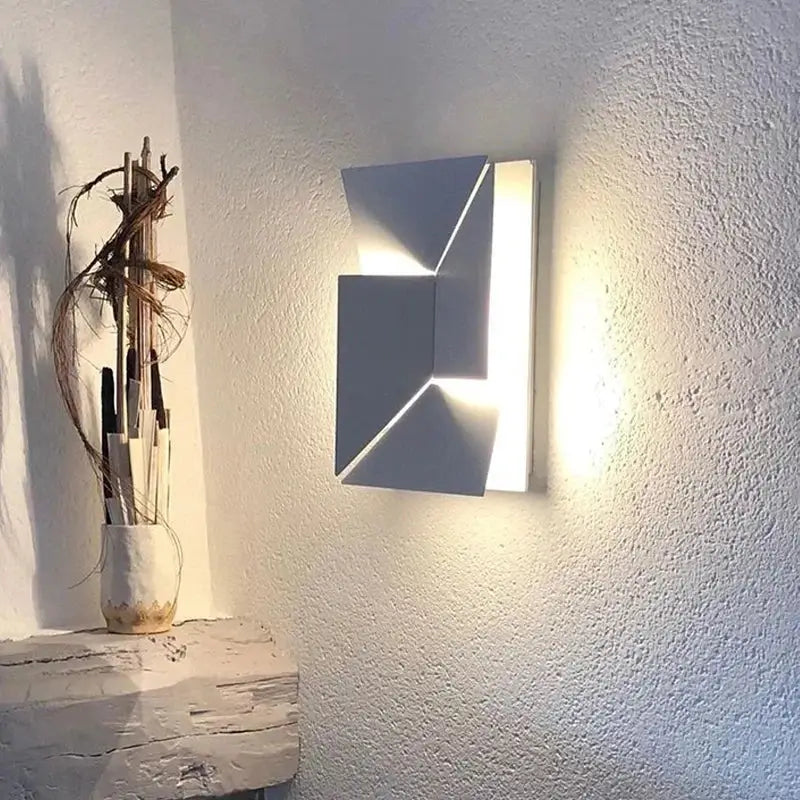 Modern white geometric decorbites grand sconce lamp with angular folded design casting warm bedroom wall light