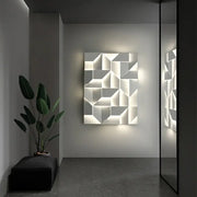 A modern geometric white grand sconce lamp featuring illuminated three-dimensional facets for bedroom decorbites grand sconce