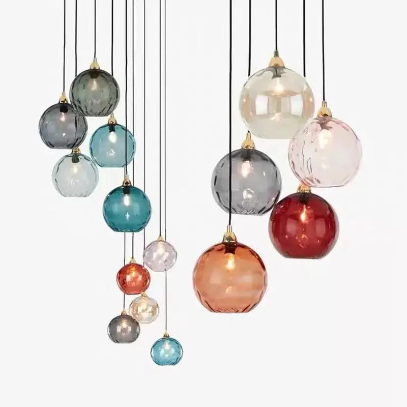 A modern cluster of decorbites glass ball pendant lights in teal amber and matte gray for kitchen decor