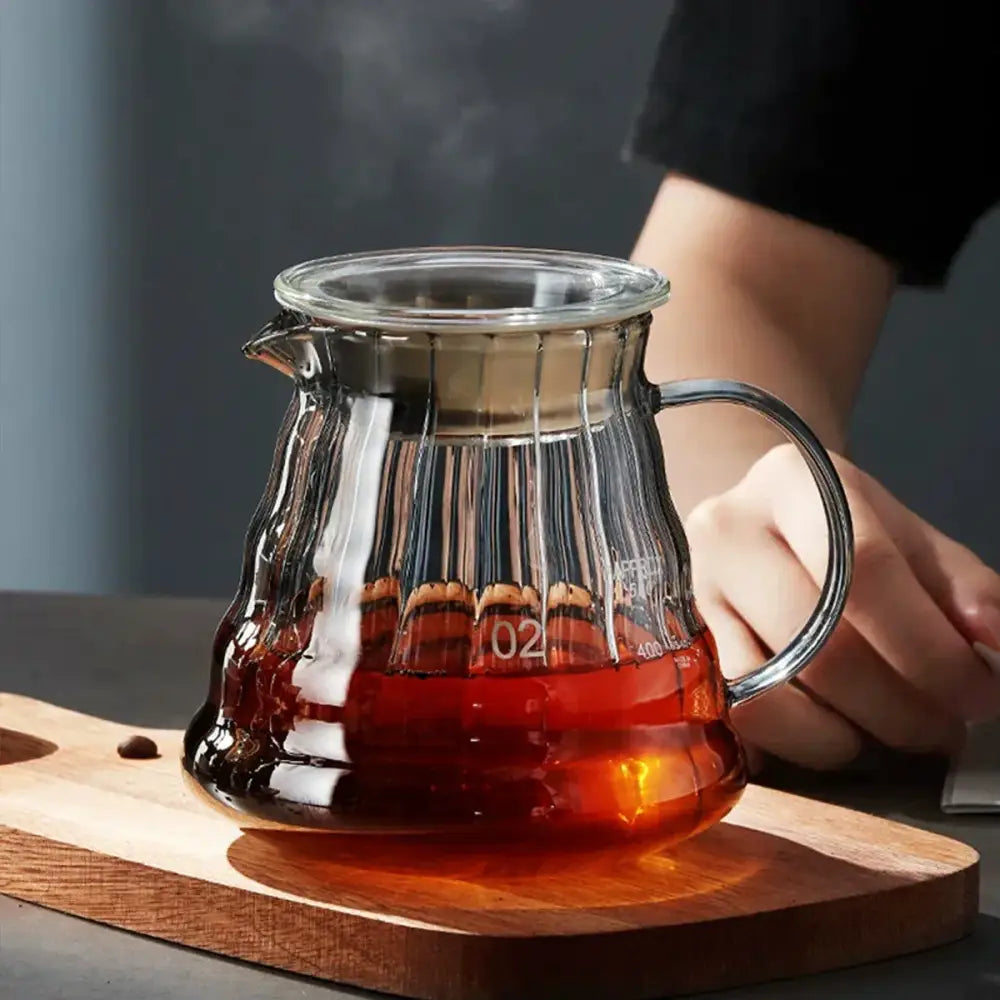 Modern glass coffee carafe with metallic lid and handle filled with rich amber liquid by decorbites glass coffee