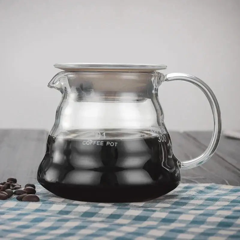 Modern glass coffee pot with stainless steel lid and handle filled with dark brewed coffee for kitchen dining use