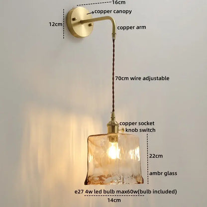 A warm amber glass copper led wall light with textured surface and brass copper hardware for bedroom use