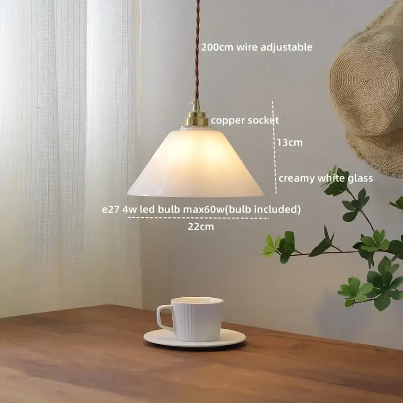 A warm glowing pendant light with creamy white glass shade and brass copper socket for dining room or kitchen island