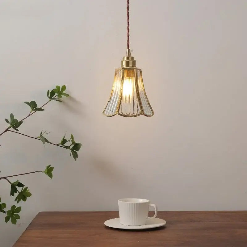 A warm-toned copper pendant light with a fluted glass shade hangs above a wooden table for dining or kitchen island use