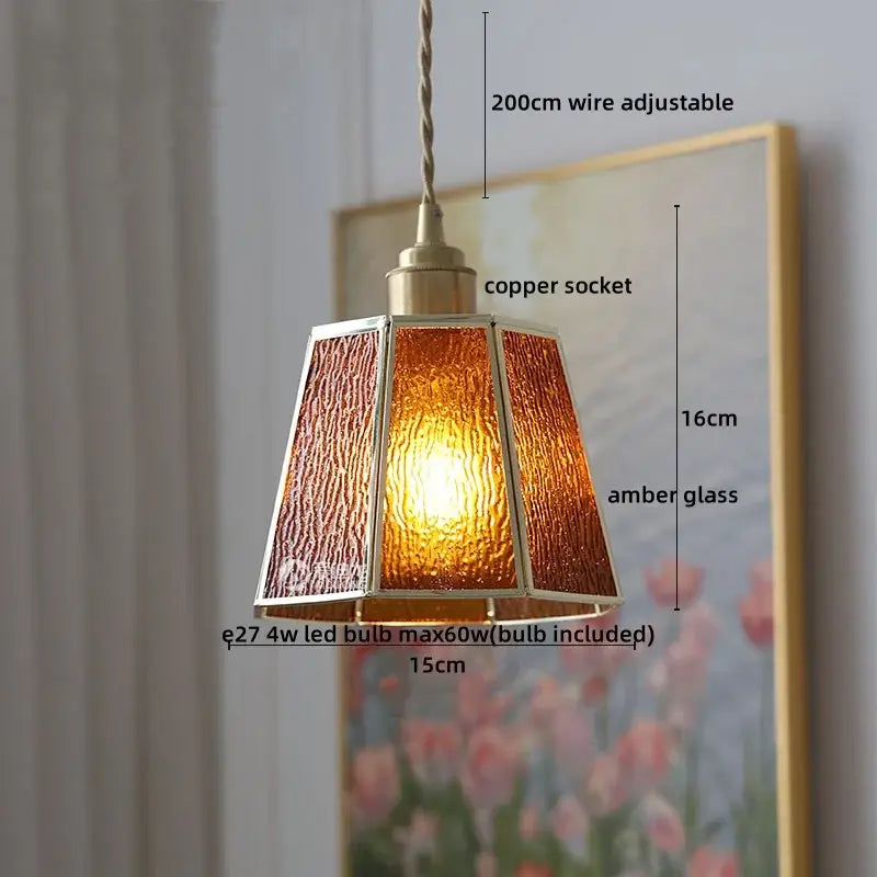 A warm amber glass copper pendant light with a faceted design and brass frame for dining room or kitchen island