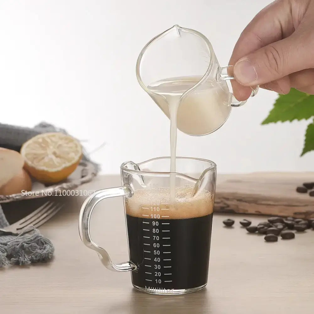 Modern glass cup measuring jug with wooden handle filled with dark coffee ideal as a milk latte jug kitchen tool